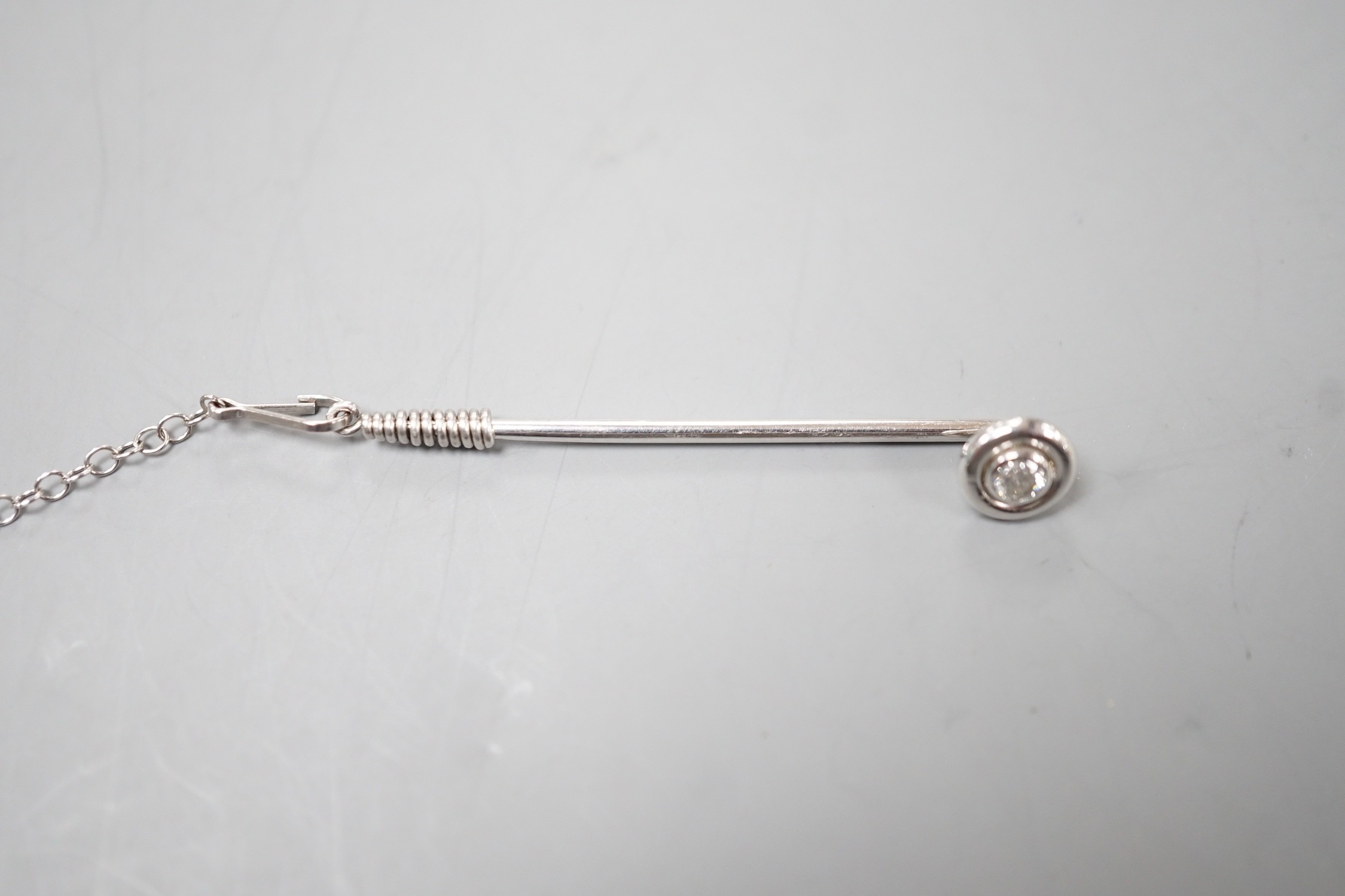 A white metal and collet set solitaire diamond tie pin, 43mm, with safety chain, gross weight 2.1 grams.